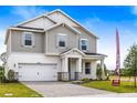 New two-story home with gray siding, stone accents, two-car garage, and manicured lawn at 1262 Champions Dr, Daytona Beach, FL 32124