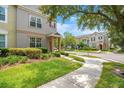 Townhome's well-maintained front yard and exterior with a sidewalk on a street corner under a sunny sky at 12963 Garridan Ave, Windermere, FL 34786