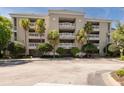 Tan condo building with balconies, palm trees, meticulous landscaping, and a large parking area in front at 1354 Centre Court Ridge Dr # 104, Reunion, FL 34747