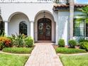 Grand entryway featuring a brick walkway, arched doorway, columns, a chandelier, and detailed wreaths at 1417 Terralago Pl, Oviedo, FL 32765