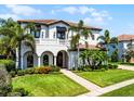 Elegant two-story home featuring a tile roof, arched entryway, a small balcony, and manicured lawn at 1417 Terralago Pl, Oviedo, FL 32765
