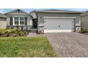 Charming one-story home featuring a brick-paved driveway and a two-car garage with stone veneer accents at 1580 Delphi Way, New Smyrna Beach, FL 32168