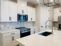 Modern kitchen with white cabinets, black hardware, stainless appliances, and quartz countertops at 16454 Silver Brook Way, Winter Garden, FL 34787