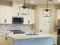Modern kitchen with white cabinets, black hardware, stainless appliances, and quartz countertops at 16454 Silver Brook Way, Winter Garden, FL 34787