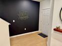 Modern entryway with wood-look floors, a dark accent wall with geometric art, and a bright white front door at 1900 Erudite Way, Winter Park, FL 32792
