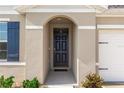 Close-up of a modern, elegant dark front door, framed by an arched entry and neutral-toned exterior at 296 Inman Blvd, Winter Haven, FL 33881