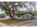 View of the home's side exterior featuring a mature tree with Spanish moss, manicured landscaping, and a well-maintained lawn at 540 Diane Cir, Casselberry, FL 32707