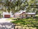 Charming home featuring a well-manicured lawn, mature trees, and a brick-accented facade at 5671 Cypress Gardens Rd, Winter Haven, FL 33884