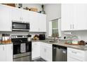 Well-lit kitchen featuring white cabinets, modern stainless steel appliances and granite countertops at 7616 Simms Ave, Orlando, FL 32812