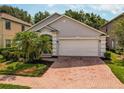 Exterior view of a single-story home showcasing a two-car garage and a brick paved driveway at 879 Nonastone Run, Casselberry, FL 32707