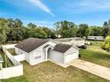 An elevated view of the charming single-Gathering home featuring a manicured lawn and an attached two-car garage at 9821 8Th Ave, Orlando, FL 32824