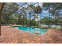 Screened-in pool area featuring a brick deck with lake view, inviting relaxation and outdoor enjoyment at 120 E Greentree Ln, Lake Mary, FL 32746