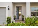 Welcoming front entrance with lush greenery, lantern and view into the living room at 13822 Destin Beach Ln, Orlando, FL 32827