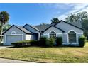 Charming single-story home with gray paint and dark trim, with a well-manicured lawn at 215 Hollowbrook Cir, Daytona Beach, FL 32114