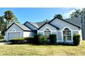 Well-maintained single-story home featuring an attached garage, manicured lawn, and lush shrubbery at 215 Hollowbrook Cir, Daytona Beach, FL 32114