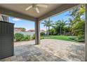 Covered back patio featuring a ceiling fan, decorative pavers, and a beautifully landscaped backyard at 2325 Bella Luna Cir, Lakeland, FL 33810