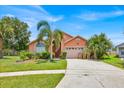 Charming single-Gathering home with a well-maintained lawn, palm trees, and an attached two-car garage at 2627 Autumn Creek Cir, Kissimmee, FL 34747
