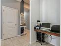 Hallway with tile flooring and neutral walls, featuring a small workstation with a laptop and office supplies at 2860 Orange Haven Way, Kissimmee, FL 34746