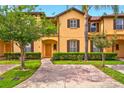Charming two-story townhome featuring a yellow facade, brown accents, and well-manicured landscaping at 3725 Calabria Ave, Davenport, FL 33897