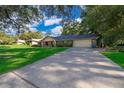 Spacious driveway leading to a brick home with lush green lawn and mature trees at 493 Princewood Dr, Deland, FL 32724