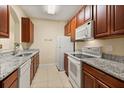 Functional kitchen featuring granite countertops, white appliances, and wood cabinets offering ample storage at 6335 Contessa Dr # 208, Orlando, FL 32829
