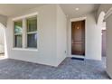 Inviting entryway with a brown front door, brick floor, window, and neutral-toned wall at 8348 Vivaro Isle Way, Windermere, FL 34786