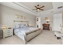Comfortable bedroom with tray ceilings, a ceiling fan, an en suite bathroom, and a king-size bed at 9846 Sw 106Th Ct Ocala, F, Ocala, FL 34481