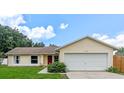 Inviting single-story home featuring a two-car garage, red front door, and green lawn at 10739 Lake Ralph Dr, Clermont, FL 34711