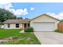 Inviting single-story home with a well-manicured lawn, attached two-car garage, and a striking red front door at 10739 Lake Ralph Dr, Clermont, FL 34711