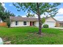 Attractive single-story home with a red door, green lawn, and an attached two-car garage at 10739 Lake Ralph Dr, Clermont, FL 34711