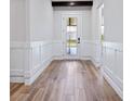 Bright foyer featuring wood-look tile flooring, wainscoting, and a front door with decorative glass panels at 13323 Panama Beach Ct, Orlando, FL 32827