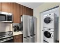 Modern kitchen with stainless steel appliances, including a refrigerator, microwave, and a stacked washer/dryer at 14501 Grove Resort Ave # 2451, Winter Garden, FL 34787