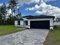Charming single-story home with a black two-car garage and beautifully paved driveway at 16463 Sw 55Th Court Rd, Ocala, FL 34473
