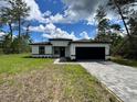 Charming single-story home with a black two-car garage and beautifully paved driveway at 16463 Sw 55Th Court Rd, Ocala, FL 34473