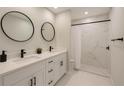 Well-lit bathroom with double vanity, sleek black fixtures, and a shower featuring elegant marble-look tile at 3325 W Washington St, Orlando, FL 32805