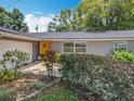 Well-maintained gray home showcasing a bright yellow front door and lush landscaping at 3443 Arnel Dr, Winter Park, FL 32792