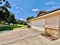 Exterior view showing the side of the garage with an extended driveway and landscaped garden bed at 5724 Pitch Pine Dr, Orlando, FL 32819