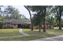 Traditional brick home featuring a well-maintained lawn, mature trees, and a cozy front entryway at 900 Red Fox Rd, Altamonte Springs, FL 32714