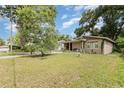 Cozy single-story home featuring a green lawn with mature trees providing shade at 205 W Division St, Deland, FL 32720
