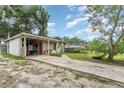 Side view of the house and long driveway with overgrown lawn at 205 W Division St, Deland, FL 32720