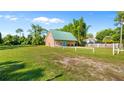 Charming tan home with vibrant blue door, green roof, and spacious front yard, nestled among lush greenery at 287 Hilltop Dr, Longwood, FL 32750