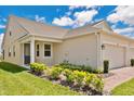 Exterior view of home featuring manicured lawn and garden, attached two-car garage, and covered entryway at 3280 Canna Lily Pl, Clermont, FL 34711
