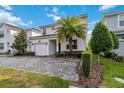 Two-story home featuring a brick driveway, palm tree, manicured bushes, and a one-car garage at 4740 Sleepy Hollow Dr, Kissimmee, FL 34746