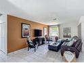 Well-lit living room featuring tile floors, a modern TV, and stylish decor at 620 Wood Dr, Kissimmee, FL 34759