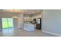 Open-concept kitchen featuring stainless steel appliances, white cabinetry, and an island with pendant lighting at 7418 Sw 129Th Ln, Ocala, FL 34473