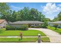 Well-maintained single story home with a lush green lawn, complimented by mature trees, shrubbery, and a convenient circular driveway at 1017 Manchester Cir, Winter Park, FL 32792