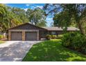 Charming home featuring a stone facade, two-car garage, lush landscaping, and a well-manicured lawn at 1343 Charlotte St, Altamonte Springs, FL 32701