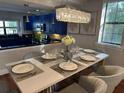 Beautifully staged dining area with modern chandelier, gray chairs and sleek, white table at 14501 Damai Ln, Orlando, FL 32821