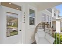 Inviting front porch with a cozy egg chair, white door with glass insert, and address numbers at 15444 Lebeau Loop, Winter Garden, FL 34787