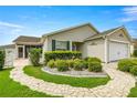 Landscaped front yard and walkway leading to the charming home with a screened-in lanai at 2528 Buttonwood Run, The Villages, FL 32162